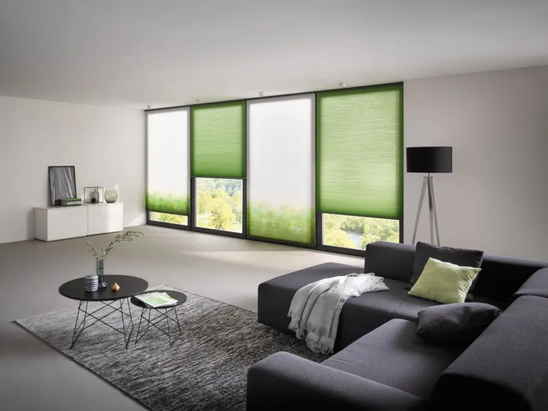 Grüne Plissees nach Maß an einer Fensterfront im Wohnzimmer