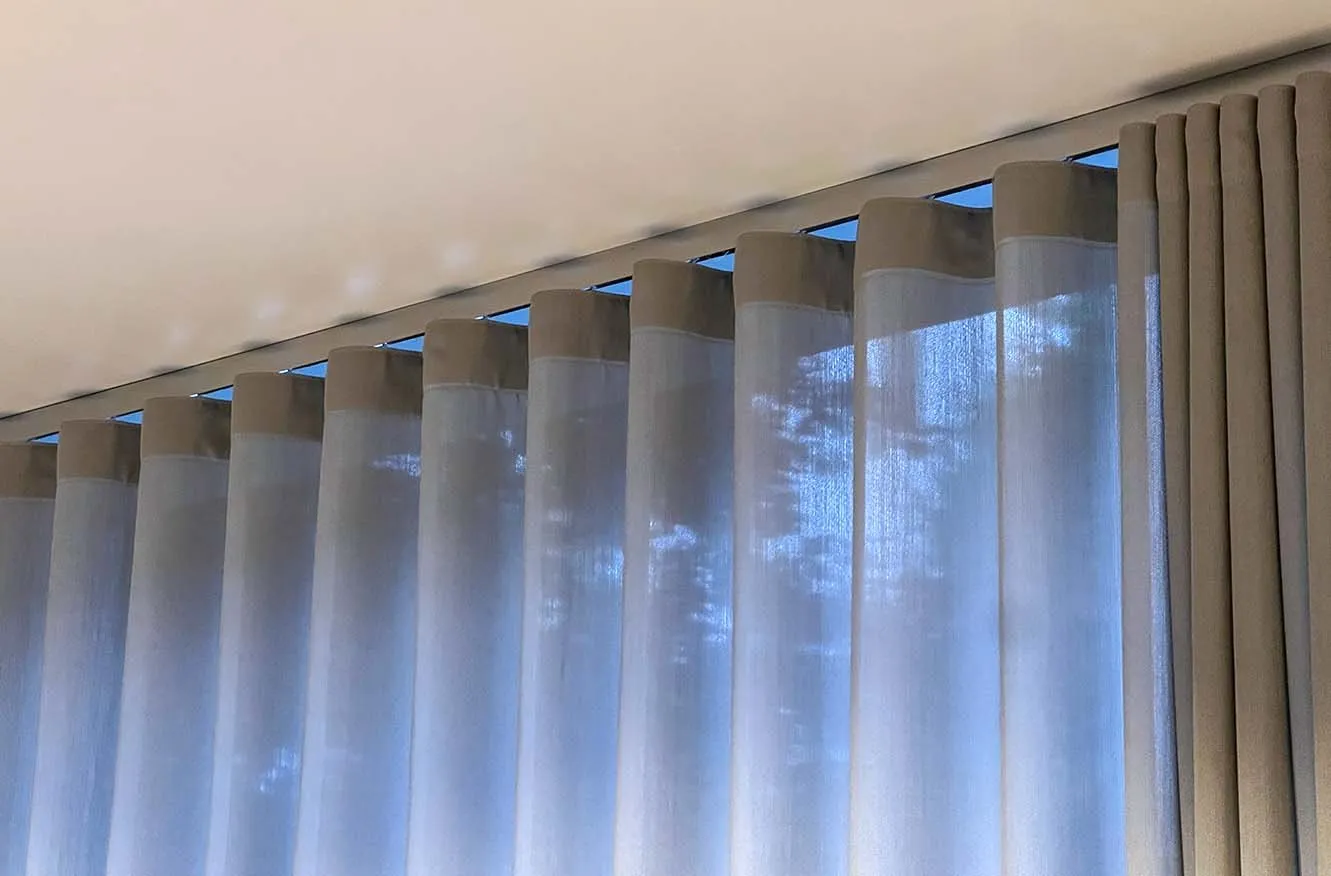 Transparenter Store und dichter Vorhang mit Wellenband an einer in die Decke eingelassenen Schiene